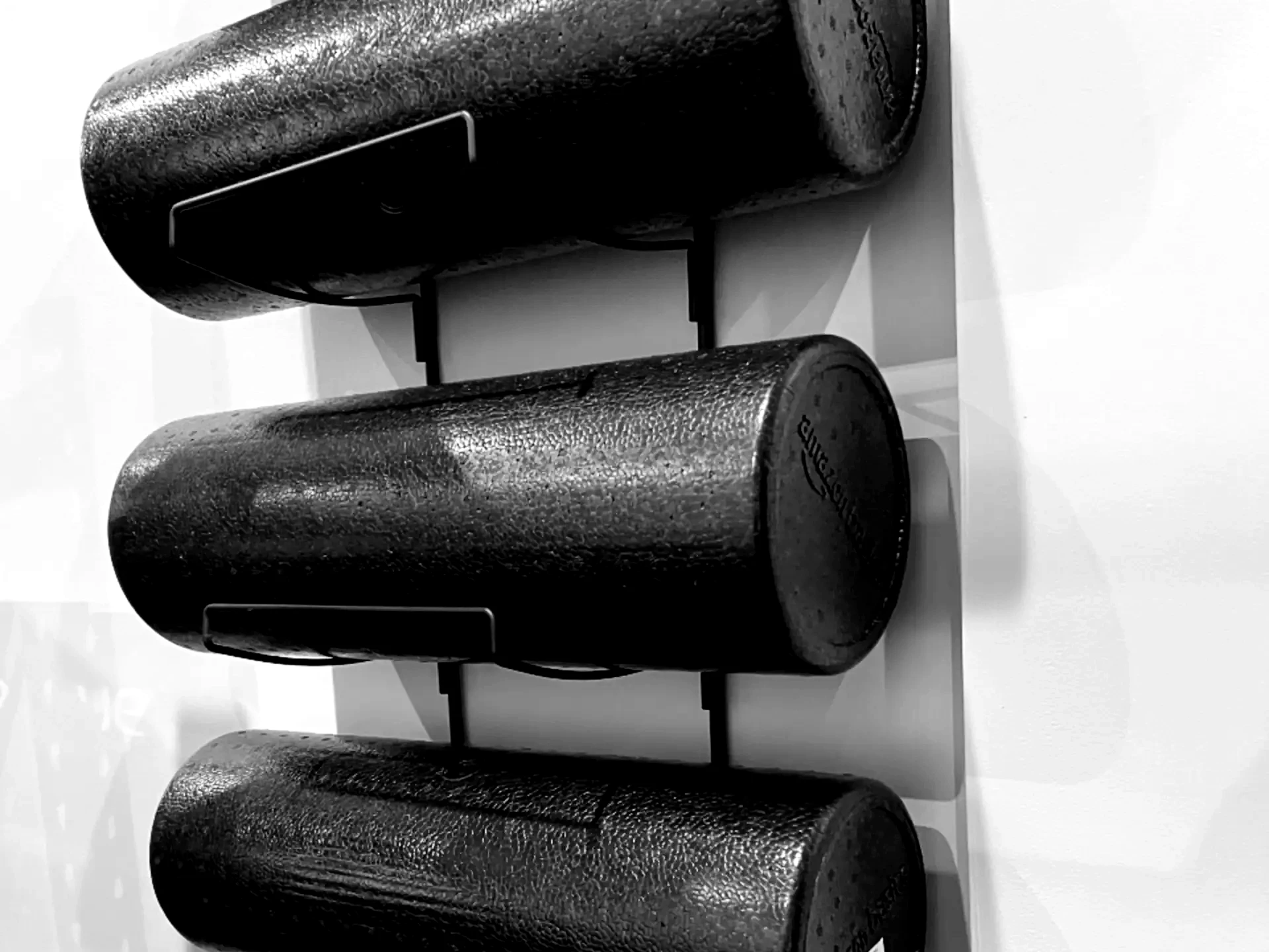 LaPlant Fitness Personal Training Studio Three black high-density foam rollers stored on a wall rack at LaPlant Fitness private training gym in Marin.